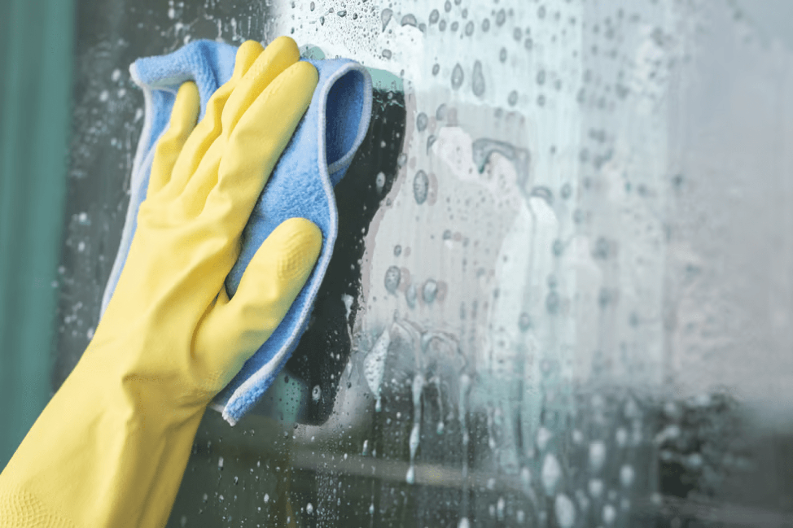 Gloved hand wiping a window during a recurring house cleaning visit